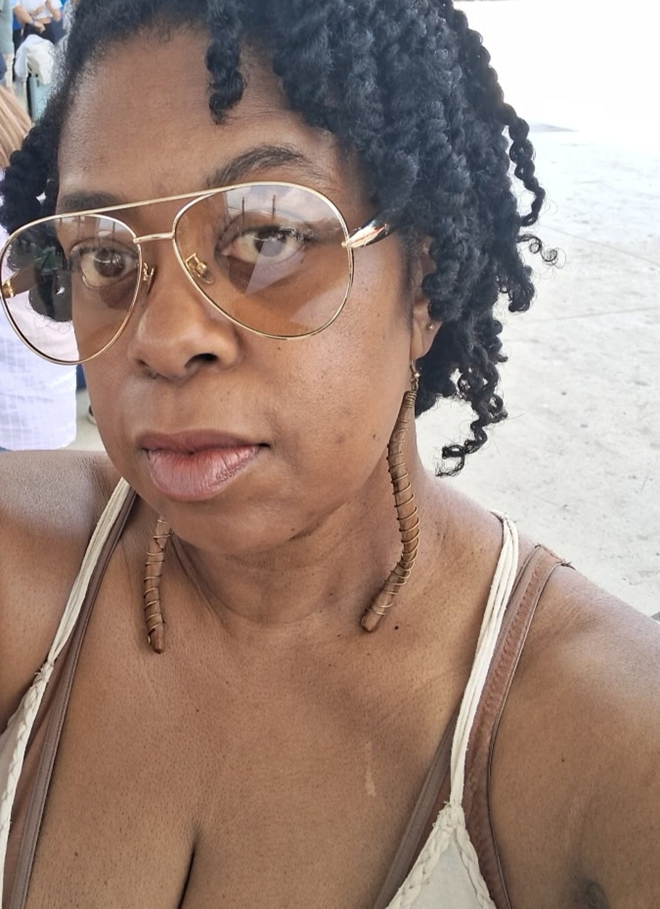 Shirl, founder of Say It Lady, wearing aviator sunglasses and gold earrings